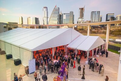 Guests spilling out of event tent with Austin TX skyline in the background.
