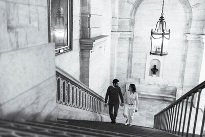 a couple walking up the stairs at the NYPL in manhattan looking at each other 