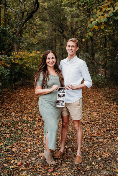 Wife and husband pose together while holding ultrasound.