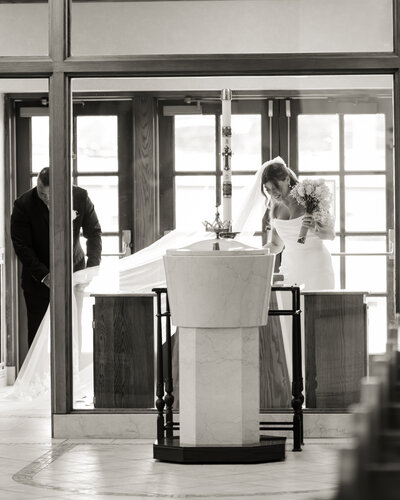 a catholic bride adjusts her wedding veil with her father before walking down the aisle for her catholic wedding at st. ann's catholic church in nashville, tn