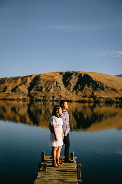 Man and Woman on a dock infront of a reflected lake enjoying the sunrise