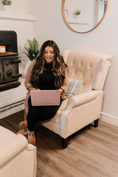 Latina sitting on a couch while on a laptop