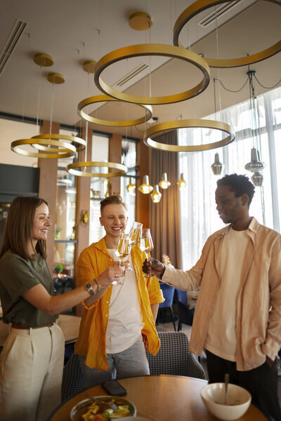 Trois jeunes collegues trinquant ensemble au champagne dans un lounge luxueux lors d'un événement d'entreprise organisé par un event planner.