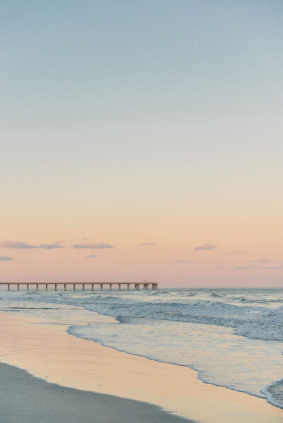 a golden sunset over the beach and pier in coastal north carolina