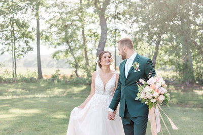 A bride and groom stroll hand in hand through the fields of New Hampshire