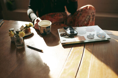 brand photographer in coffee shop with phone and laptop in southern Alberta. 