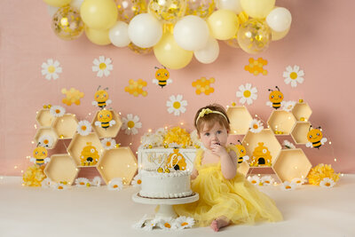 columbus-ohio-first-birthday-baby-girl-in-yellow-tulle-dress-with-pink-backdrop-bumblebee-honey-sweet-as-can-bee-theme-cake-smash