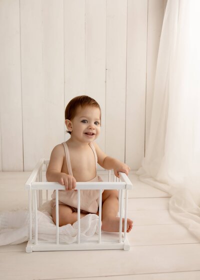 baby in a prop by the window in simple and neutral set up in studio in Edmonton