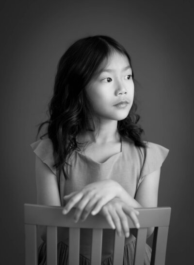 black and white portrait of child looking away with dark background