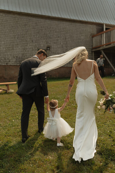 bride groom and flower girl walk towards wedding venue in pei
