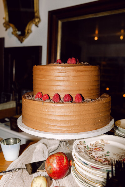 Elegant minimalist chocolate wedding cake with raspberry accents at a backyard wedding reception in Richmond, Virginia, photographed by Editorial Wedding Co.