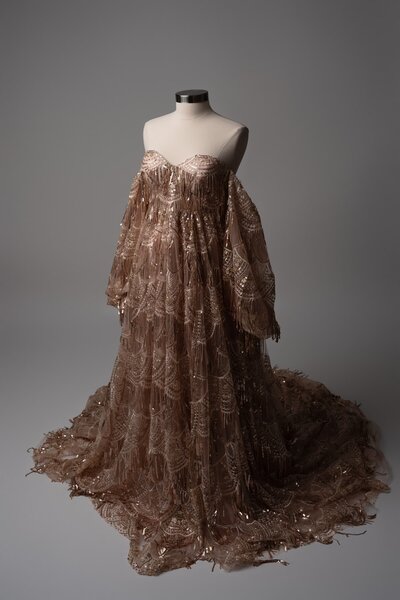Sequin-covered rose-toned maternity dress with deep V neckline, shown on mannequin