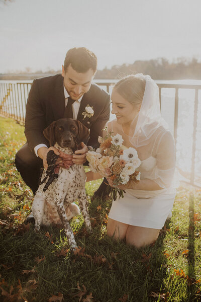 Couple poses with dog in grass for elopement photo