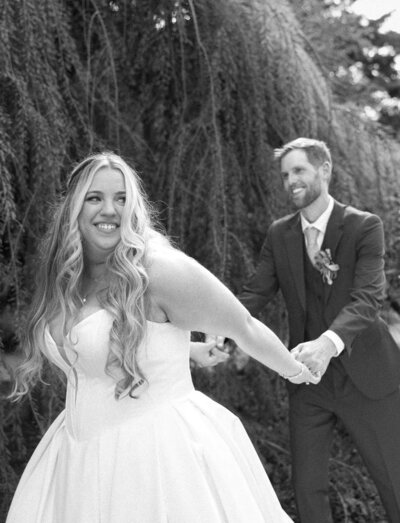Bride leading groom outdoors, smiling