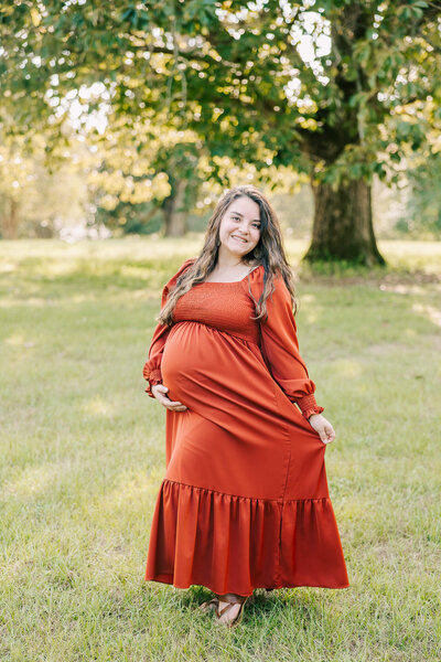 Expecting mom in mauve dress  having maternity portrait session in an open field with her husband and son.