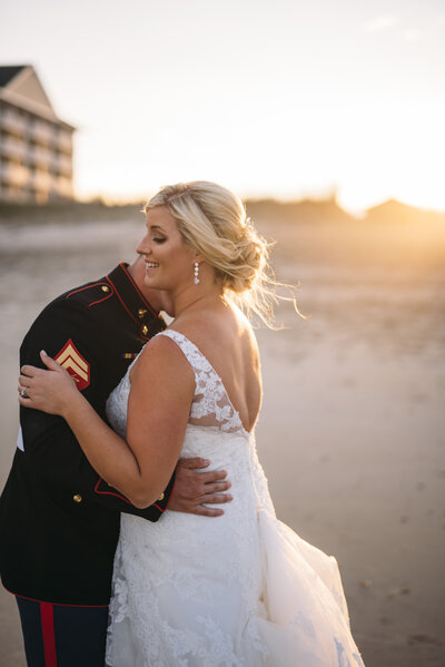bride and groom hugging while standing on beach