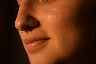 Closeup of two small hoops in a woman's nose: one's in the nostril and one's in the septum.