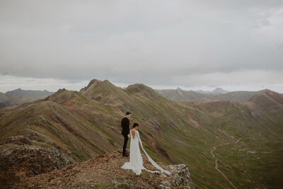 Couple stands on the edge of a mountain in Telluride