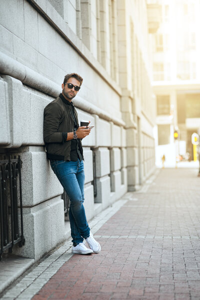 portrait-serious-man-with-coffee-outdoor-waiting-with-sunglasses-relax-communication-with-app-fashion-shades-person-with-smartphone-commuting-street-confident-usa