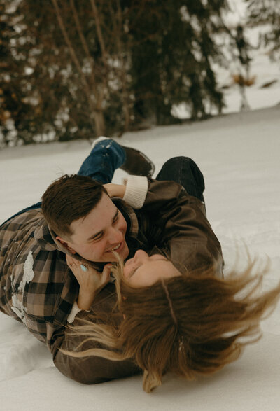 A husband and wife holding each other and smiling as their 3 kids run towards them.