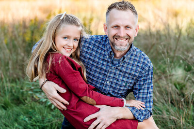 Connecticut family photographer captures smiling father and daughter in coordinating plaid and burgundy outfits during outdoor fall session