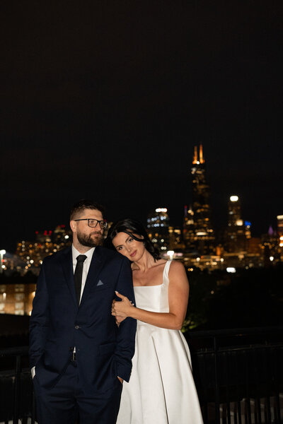 Bride and groom standing in front of a city skyline at night. Gorgeous elopement flash photography.