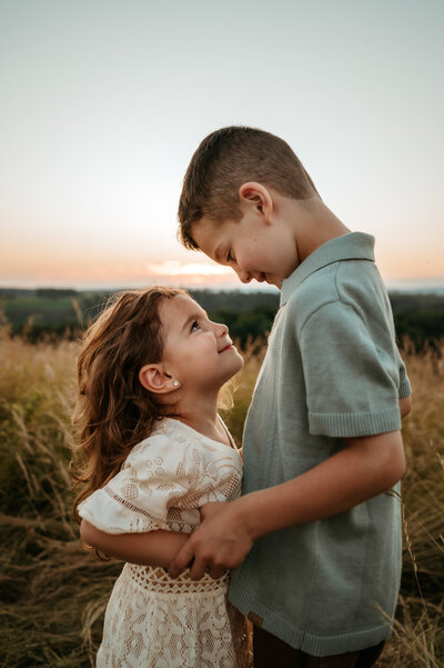 An older brother smiling and looking down at his little sister. 