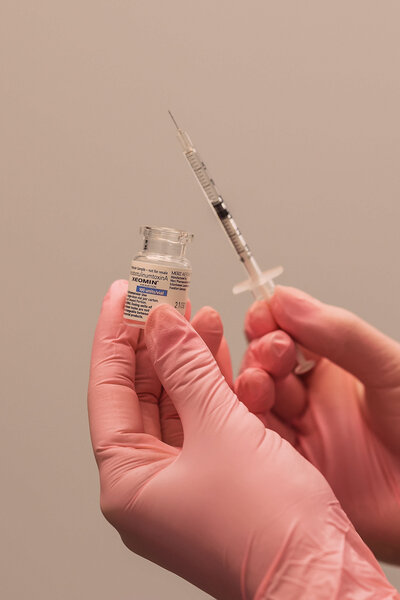 person holding a bottle of botox and a needle