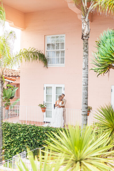 Bride and groom snuggling on balcony at La Valencia La Jolla Wedding Venue by Hayes and Bree Sherr, Wedding Photography and Videography.