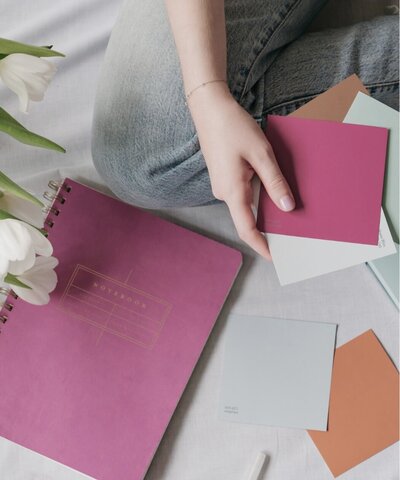 Emma, a brand and website designer, holding paint chips while selecting a color palette.