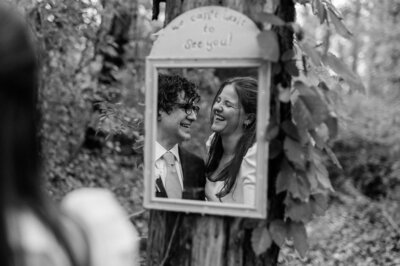 Bride and groom smiling at each other in mirror reflection