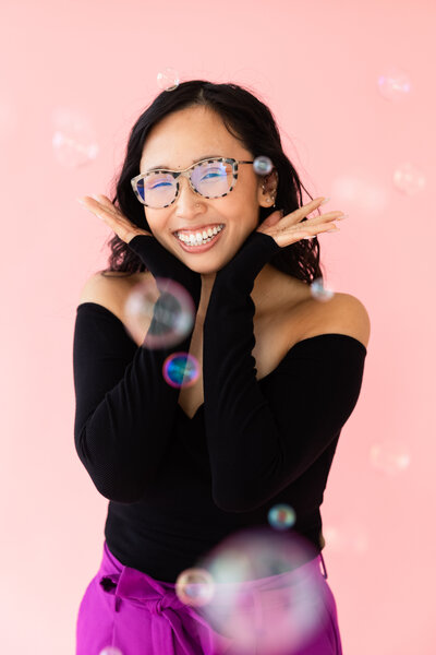 Portrait of Anh Nguyen, photographer behind Anh Point Photography, smiling at the camera through bubbles.