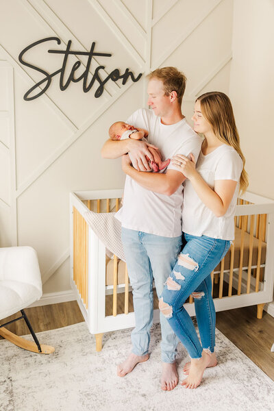 Family of 3 snuggling together in their son's nursery at their newborn lifestyle session in Laramie, Wyoming.