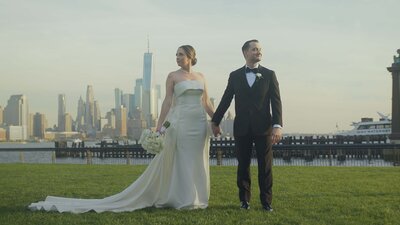 A couple holding hands and walking in front of the NYC skyline.