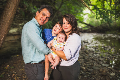 Beautiful fall family portrait in Pittsburgh park featuring parents and young daughter surrounded by vibrant autumn foliage. Professional family photography capturing genuine moments and connections by top Pittsburgh photographer.