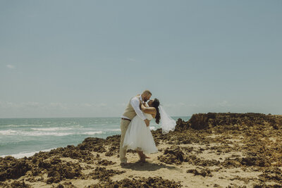 bride and groom lean in for a kiss on the beach in south florida