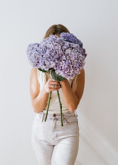 Floral designer holding a bouquet of purple hydrangeas