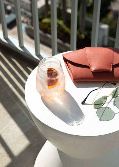 aperol spritz, orange clutch, and sunglasses on an outdoor table