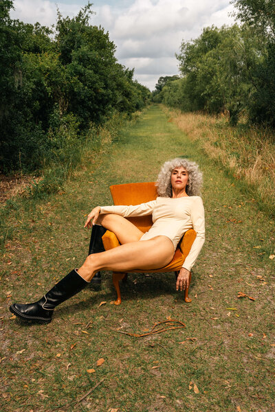 Older woman model sitting on orange chair outdoors