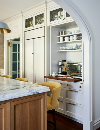Boston kitchen designer created a custom white kitchen with marble counters and Urban Electric lighting fixtures, blending timeless elegance with modern style.