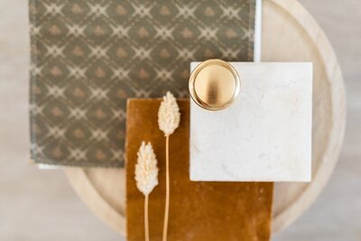 Brass handle, marble backsplash, textured sage wallpaper, and flooring samples in Carlsbad, California.