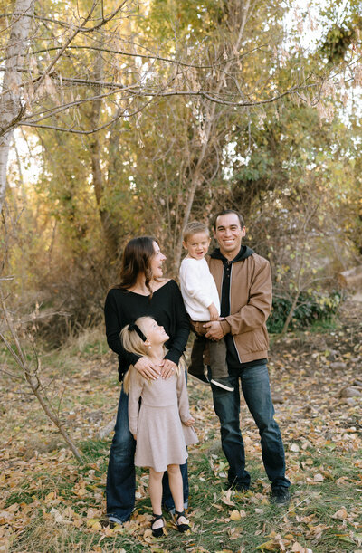 Couple holding hands while walking through a sunlit field in the Idaho foothills during an engagement session