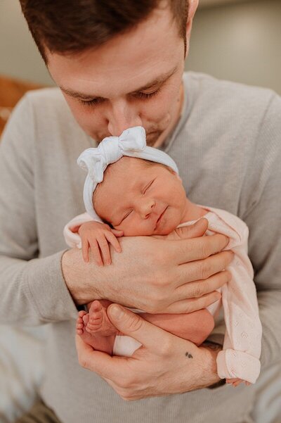 Photo of newborn girl snuggled in dad's arms during Vancouver newborn photography session by Kindred Photography.