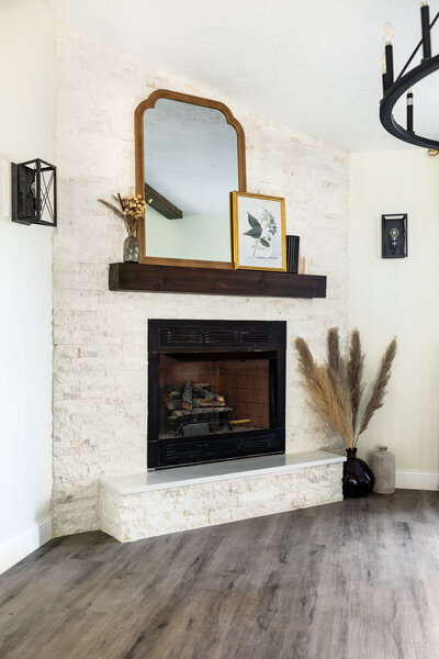 Custom built and stained fireplace mantel with mirror, frames and vases as decor.