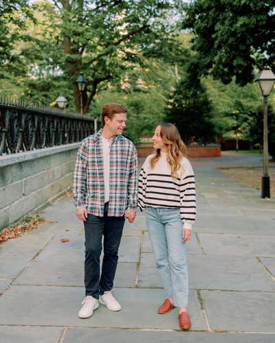 A newly engaged couple holds hands outdoors.