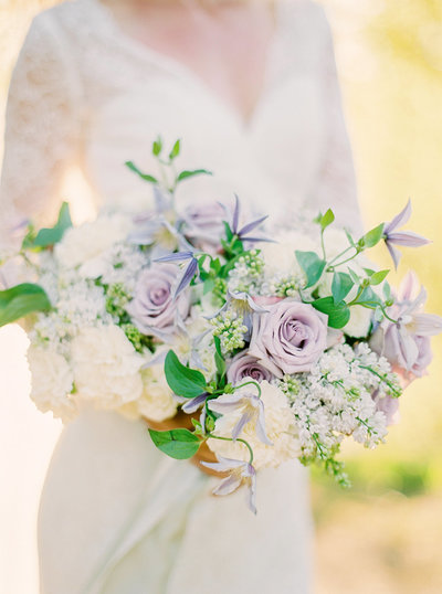 Bride with lace dress and wedding bouquet with dusty purple and white summer flowers
