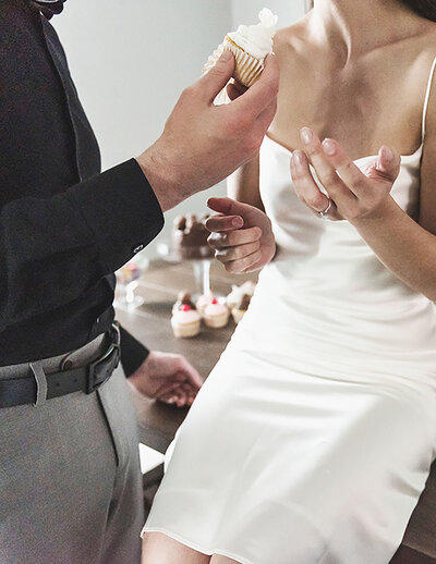 Couple sharing a cupcake during romantic, editorial-style engagement session in Michigan