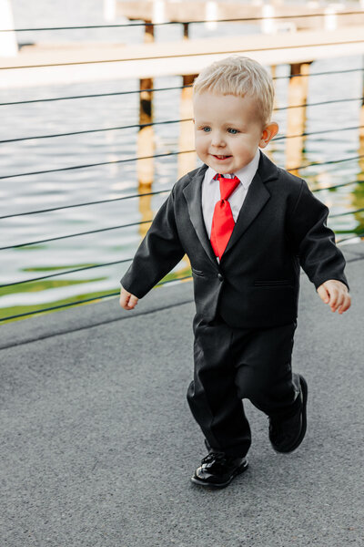 Little boy ring bearer running in wedding tuxedo