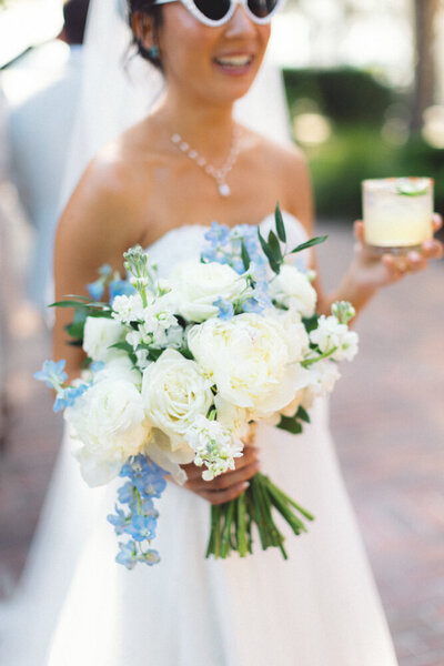 bride holding bouquet and drink