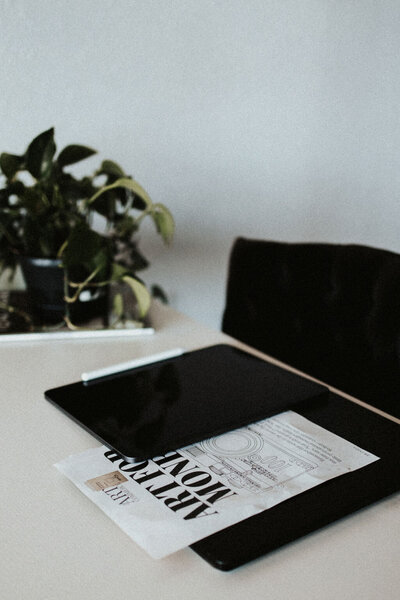 An iPad Pro and Laptop lay together with a magazine page in between.